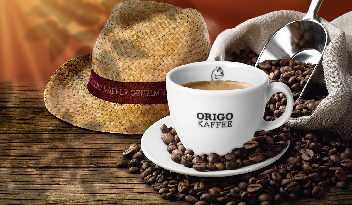 Eine Tasse Kaffee im Vordergrund mit einem Strohhut und einem Jutebeutel Kaffeebohnen im Hintergrund