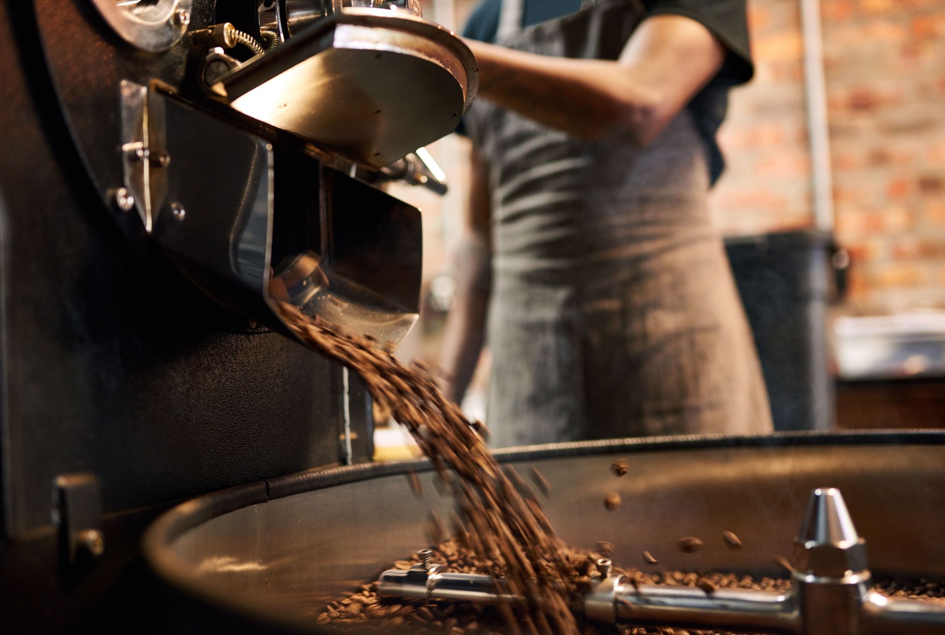 Employee operates the supply of coffee beans to the drum in the drum roasting process